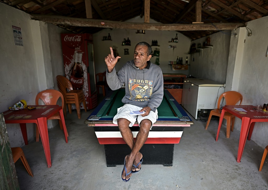 Paulo Gomes Bizerra, who lives across a dirt road from the "little house," flashes an "L" for "Lula" after belting out a song he wrote for the leftist icon