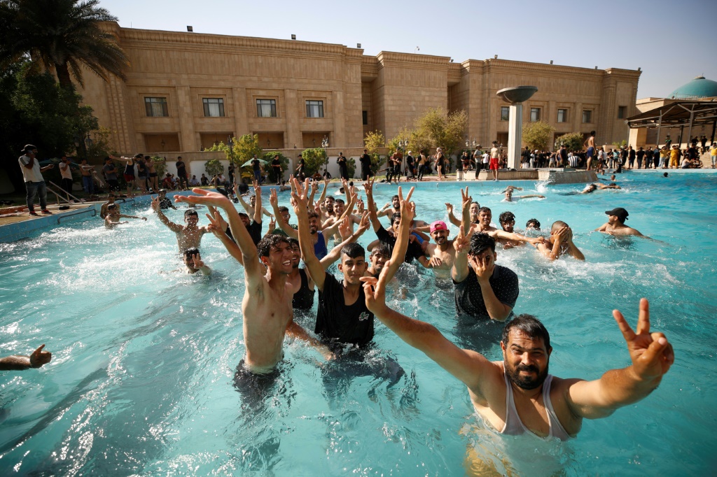 Supporters of Moqtada Sadr swim in the pool at the Republican Palace after storming the government headquarters on Monday